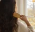 Femme brossant ses longs cheveux bruns près d'une fenêtre en automne