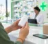 Complément alimentaire en pharmacie ou en ligne : une cliente lit l'étiquette d'un flacon au comptoir d'une pharmacie au Maroc
