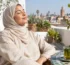 Femme portant un foulard qui profite du soleil sur une terrasse au Maroc, source naturelle de vitamine D